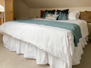 a large bed with white sheets and pillows at Birch Tree Cottage in Edzell