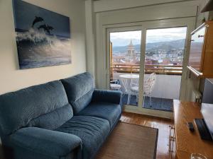 a living room with a blue couch and a balcony at Estudio con vistas a la ciudad in Ourense