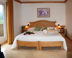 HOTEL DOLOMITI di De Martin D Oscar في كوميليكو سوبيريور: غرفة نوم بها سرير كبير وعليه زهور
