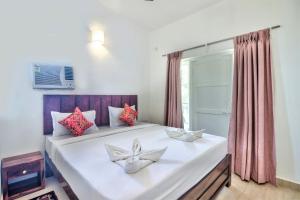 a bedroom with a large white bed with a window at Santa Monica Resort - Calangute in Calangute
