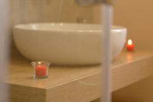 una vela en un vaso sobre una mesa de madera con fregadero en ARTrinacria Apartments - Qubba en Palermo