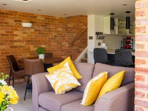 uma sala de estar com um sofá com almofadas amarelas em Mallard Cottage em Winchester
