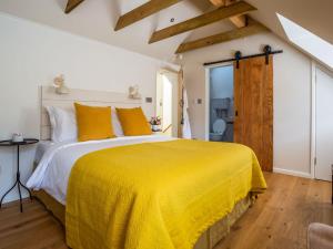 ein Schlafzimmer mit einem großen Bett mit gelber Tagesdecke in der Unterkunft Mallard Cottage in Winchester
