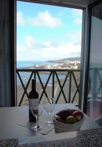 un tavolo con un cesto di frutta, una bottiglia e bicchieri di Casa Sol y Mar a Garachico