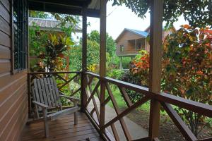 a wooden porch with a chair sitting on it at Mana Kai Camping & Cabins in San Ignacio