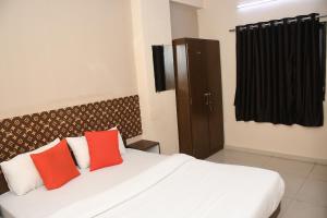 a bedroom with a bed with two red pillows at Hotel Nawanagar Residency in Jamnagar