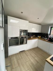 a kitchen with white cabinets and a wooden floor at Large king-size bedroom with modern fitted kitchen in Greater London in Eltham