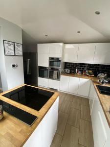 a kitchen with white cabinets and a black refrigerator at Large king-size bedroom with modern fitted kitchen in Greater London in Eltham