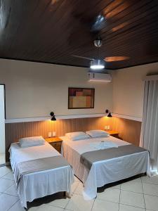 two beds in a hotel room with lights on the wall at Pousada Kactus in São João da Barra