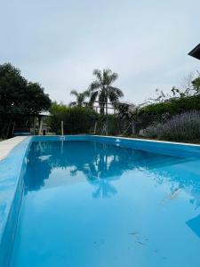 una grande piscina blu con alberi sullo sfondo di Cabaña La América a Ezeiza