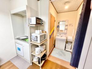 a small kitchen with a stove and a microwave at Petit Hotel 017 - Vacation STAY 36979v in Tokushima