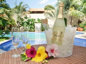Una botella de champán y dos copas en una mesa con flores. en Pousada Surucuá - Bonito MS, en Bonito