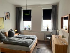 a bedroom with a bed and a desk and windows at Schmuckstück im Herzen Rostocks mit grüner Oase in Rostock