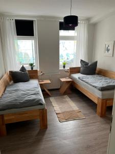 a bedroom with two beds and two windows at Schmuckstück im Herzen Rostocks mit grüner Oase in Rostock