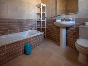 a bathroom with a tub and a sink and a toilet at 250 yo Tal-Bambinu Guesthouse in Xagħra