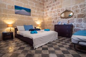 a bedroom with a bed in a stone wall at 250 yo Tal-Bambinu Guesthouse in Xagħra