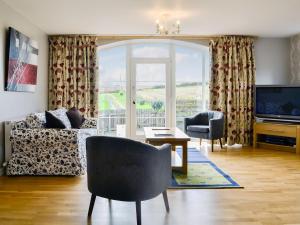 a living room with a couch and a tv at Little Harrowfield in Bankfoot