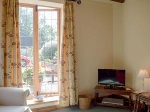 ein Wohnzimmer mit einem TV und einem Fenster in der Unterkunft Y Bwthyn-uk31367 in Tregynon