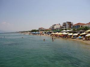 a beach with umbrellas and people in the water at Aegean Hotel in Agia Triada