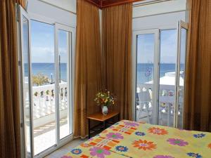 a bedroom with a bed and a balcony with the ocean at Aegean Hotel in Agia Triada