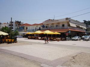 two people walking down a street with yellow umbrellas at Aegean Hotel in Agia Triada
