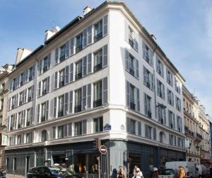 Un bâtiment blanc avec des gens qui marchent devant lui dans l'établissement Holiday Inn Paris Elysées, an IHG Hotel, à Paris