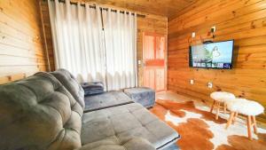 a living room with a couch and a flat screen tv at Casa Completa | 2 Suítes + Jardim com Fogo de Chão in Urubici