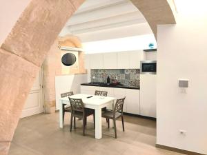 a white kitchen with a white table and chairs at Corinzia Casa Vacanze in Syracuse