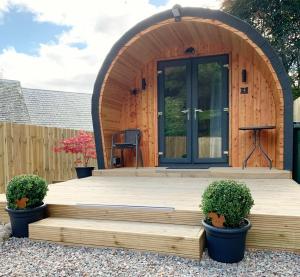 een houten hut met een houten terras en een deur bij Loch Ness Woodland Pods in Drumnadrochit