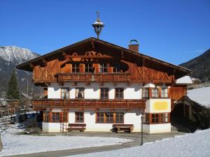 a large wooden building in the snow with a bench at Nockhof in Neustift im Stubaital