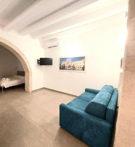 a living room with a blue couch and a bed at Corinzia Casa Vacanze in Siracusa