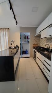 a kitchen with white cabinets and a black counter top at Casa da lagoa in Porto Seguro