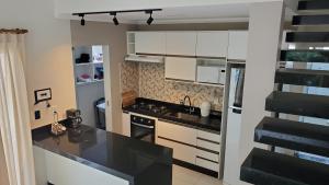 a kitchen with white cabinets and a black counter top at Casa da lagoa in Porto Seguro