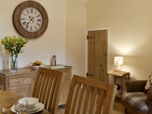a living room with a table and a clock on the wall at Bwthyn Talaran in Dolgellau