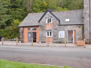 a stone house with a fence around it at Printmakers Cottage in Bellanoch