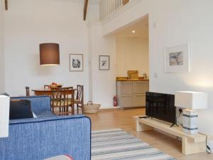 uma sala de estar com um sofá azul e uma televisão em Printmakers Cottage em Bellanoch