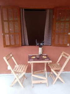 een tafel en twee stoelen naast een raam bij Vila Sincorá - Chalé para 4 pessoas com cozinha a 2 km da portaria da Cachoeira do Buracão in Ibicoara