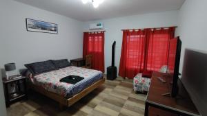 een slaapkamer met een bed en twee rode gordijnen bij Depto para turistas - Mago Blanco in Godoy Cruz