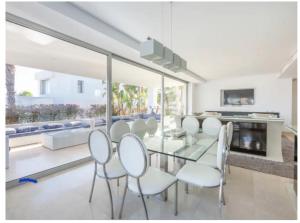 comedor con mesa de cristal y sillas blancas en Magnifique villa contemporaine, en Marbella