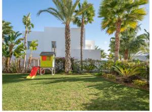 een achtertuin met palmbomen en een speeltuin bij Magnifique villa contemporaine in Marbella