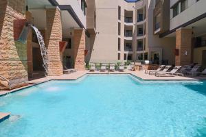 a swimming pool in a hotel with chairs and a building at Exquisite Home-Walk Score 81-Shopping District-King Bed-Parking -G3021 in Scottsdale