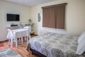 Schlafzimmer mit einem Bett, einem Tisch und einem TV in der Unterkunft Pousada Vegas in São Roque