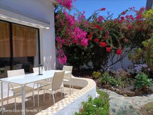een witte tafel en stoelen op een patio met bloemen bij Schöne Wohnung in Puerto de la Cruz mit Garten. in Puerto de la Cruz