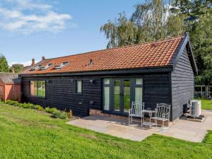 a small black house with two chairs and a table at Blackwell Barn in Raydon