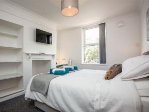 a white bedroom with a large bed and a window at Herons Haven - Uk31452 in Paignton