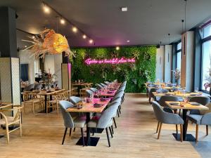 un comedor con mesas, sillas y plantas en Emily Hotel Leipzig Neue Messe, en Leipzig