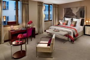 パリにあるマンダリン オリエンタル パリのベッド、テーブル、椅子が備わるホテルルームです。