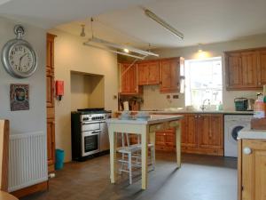 a kitchen with wooden cabinets and a table and a clock at Culpee House in Newton Stewart