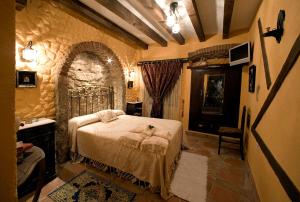 1 dormitorio con cama y pared de piedra en Casa Rural Margarita II, en Montánchez