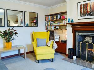 a yellow chair in a living room with a fireplace at Footdee Cottage in Aberdeen